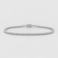 A silver tennis bracelet with a continuous row of small clear gemstones and a clasp closure, photographed on a light gray background.