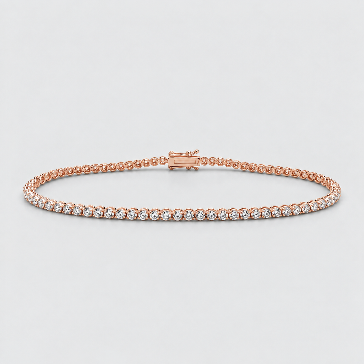 A rose gold tennis bracelet with a row of small clear gemstones, displayed on a light gray background.