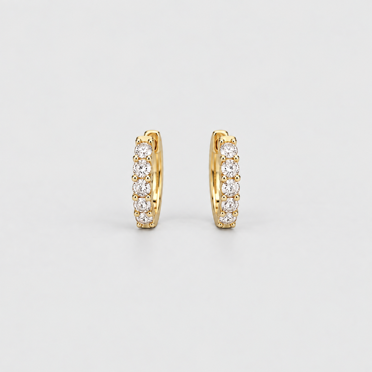 Classic yellow gold huggie hoop earrings with a row of sparkling round lab grown diamonds on a light gray background