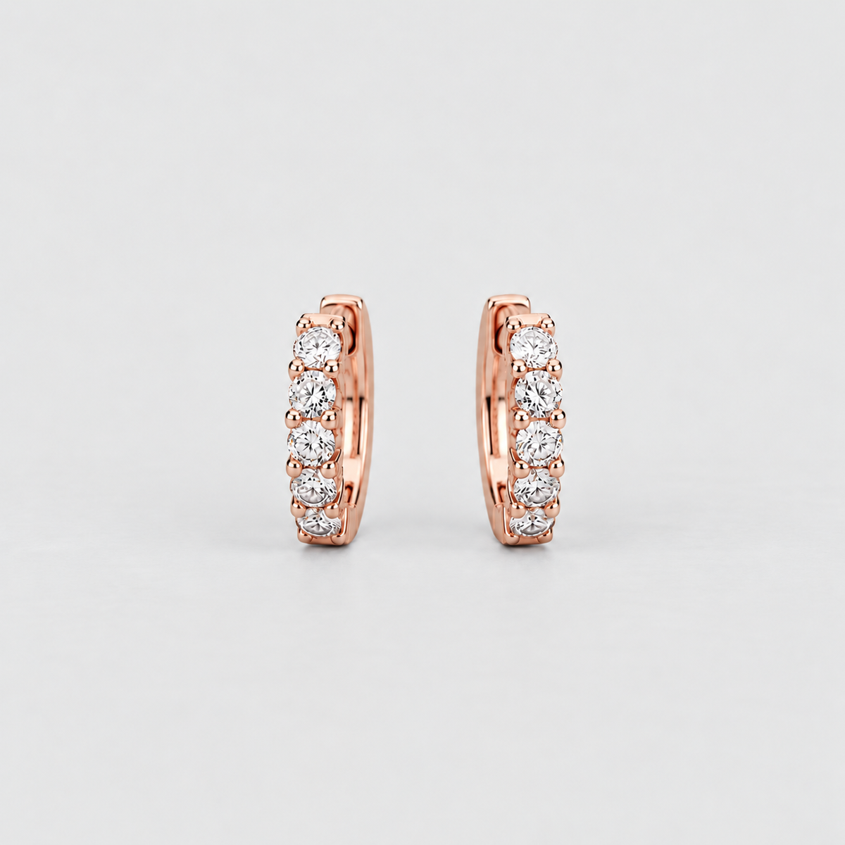 Pair of rose gold huggie earrings featuring four prong-set round lab grown diamonds each