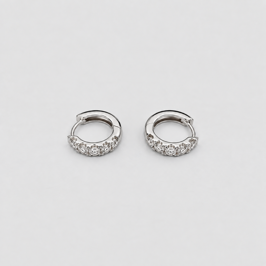 Elegant white gold hoop earrings with a curved row of sparkling round cut lab grown diamonds, flat lay