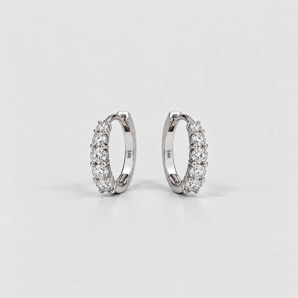 14K white gold lab grown diamond huggie hoop earrings with five round cut diamonds each, angled view