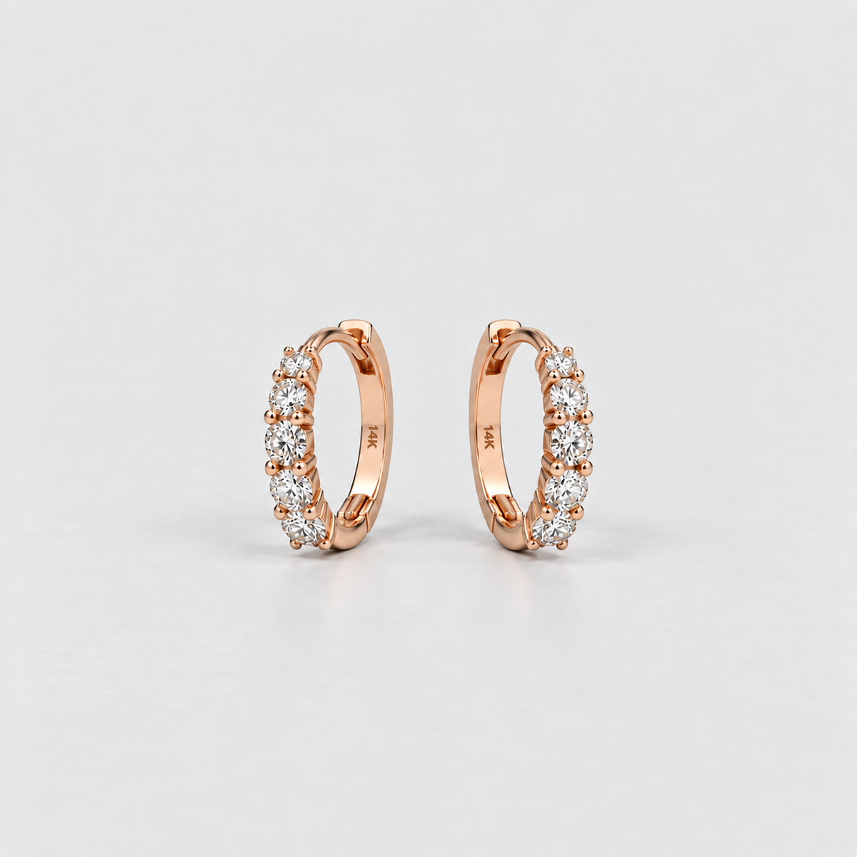 14K rose gold lab grown diamond huggie hoop earrings with five round cut diamonds each, angled view