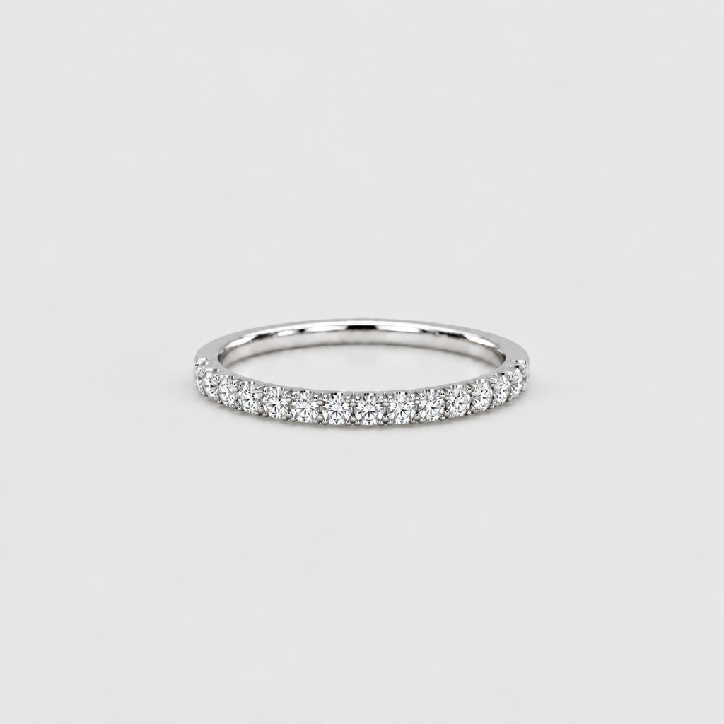 A thin silver diamond band ring with a row of small round-cut diamonds set on a plain light gray background.