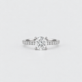A classic solitaire engagement ring featuring a round brilliant-cut diamond set in a four-prong silver band with pavé diamonds on the shoulders, photographed on a clean light gray background.