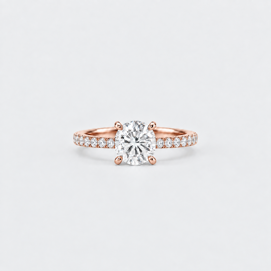 A rose gold solitaire engagement ring with a round-cut center diamond and pavé-set diamonds along the shoulders, centered on a light gray background.