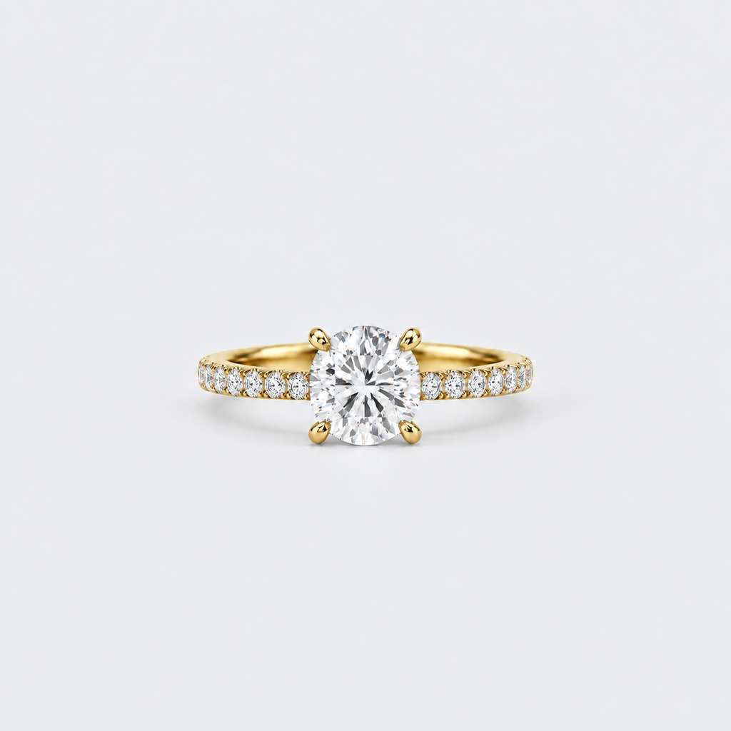 A yellow gold solitaire engagement ring featuring a round brilliant-cut center stone and a pavé-set diamond band, shown on a clean light gray background.
