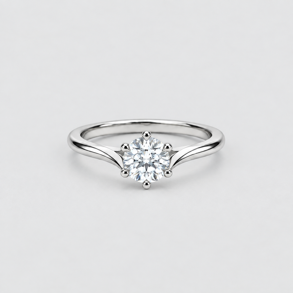 A silver solitaire engagement ring with a round brilliant-cut diamond center stone, set on a plain light gray background.