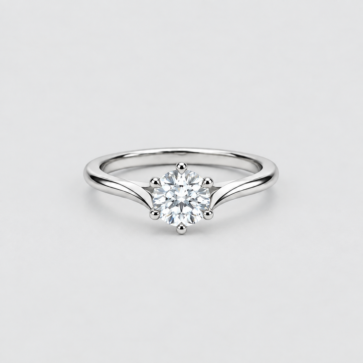 A silver solitaire engagement ring with a round brilliant-cut diamond center stone, set on a plain light gray background.
