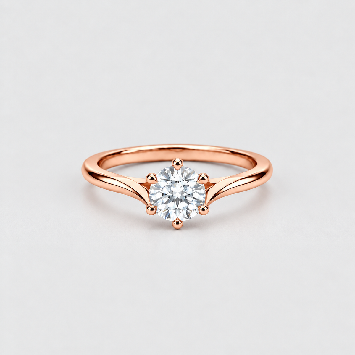 A rose gold solitaire engagement ring with a round brilliant-cut diamond set in a six-prong setting, shown on a clean light gray background.