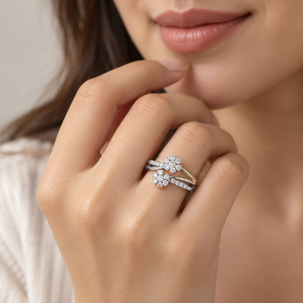 A close-up lifestyle shot of a woman's hand wearing a delicate double ring set with small clear diamonds. The ring features a yellow gold band with a floral cluster of diamonds and a silver-toned band with pavé-set diamonds.