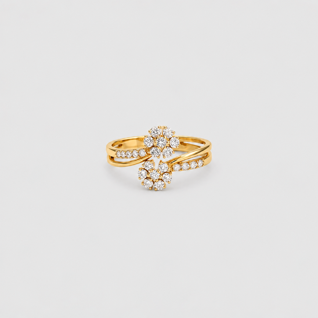 A gold ring featuring a floral cluster design set with clear gemstones, photographed on a light gray background.