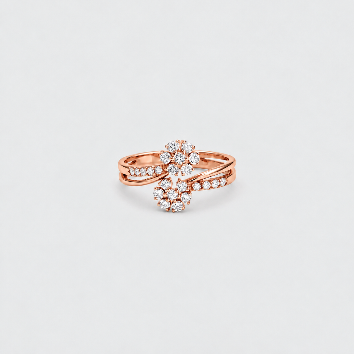 A rose gold ring with a floral cluster design set with clear gemstones, photographed on a clean, light gray background.
