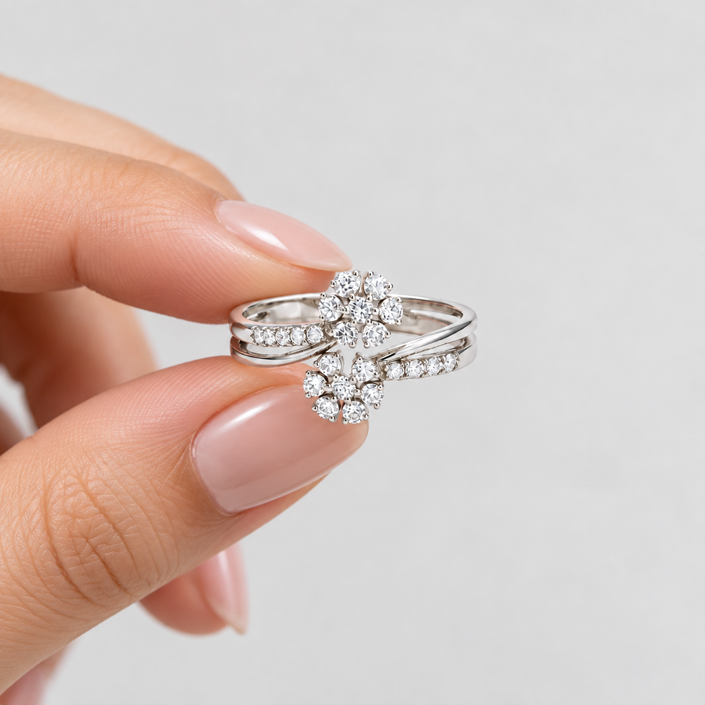 A silver-toned double ring set with round-cut clear stones, held between fingers against a light gray background.