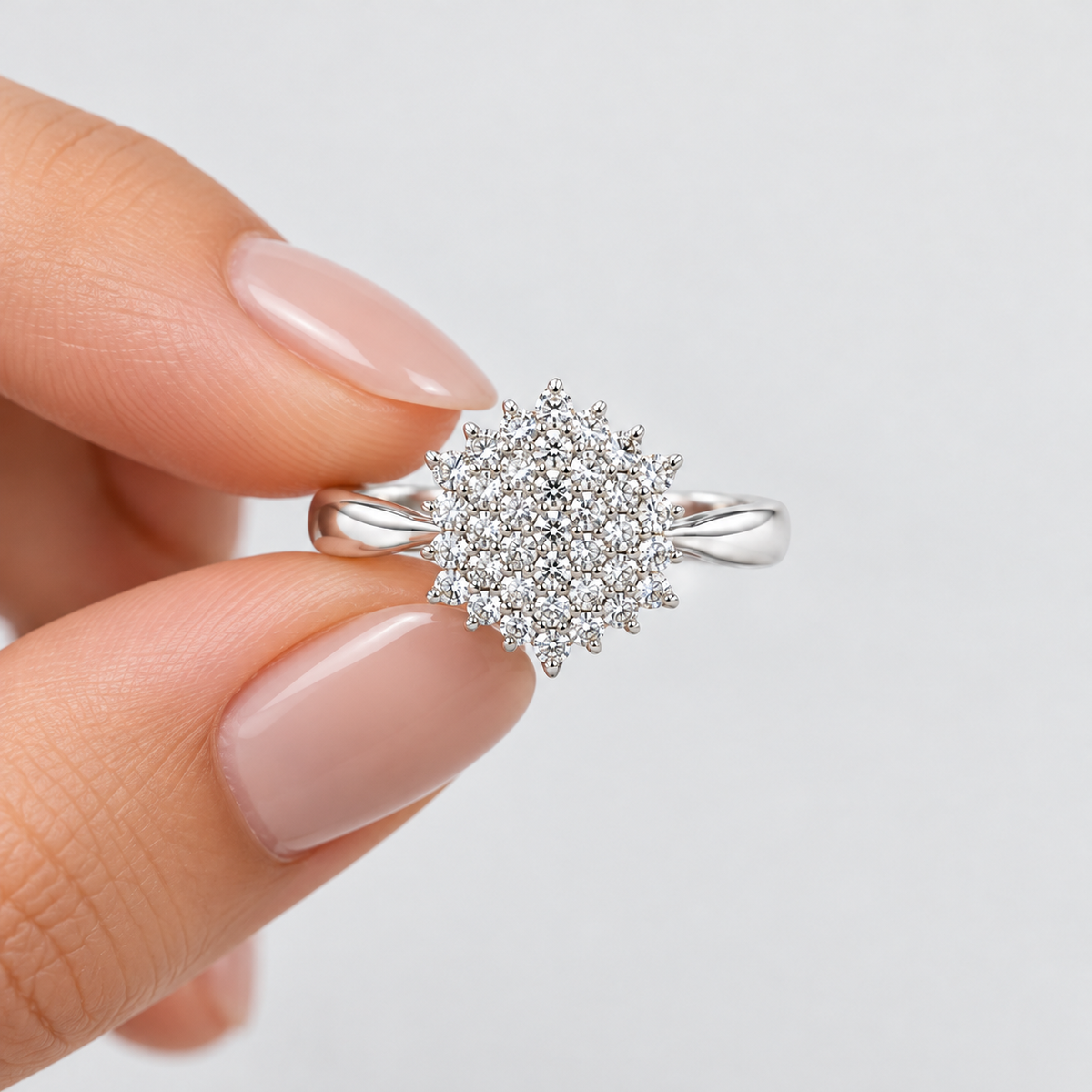 Women's diamond cluster ring in white gold or platinum held by hand