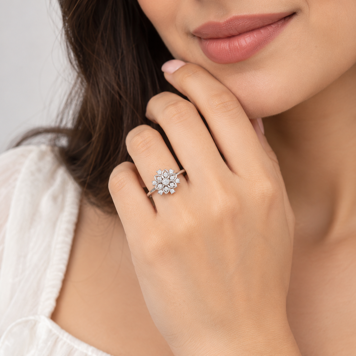 Close-up of a sparkling round diamond cluster engagement ring on a woman's finger.