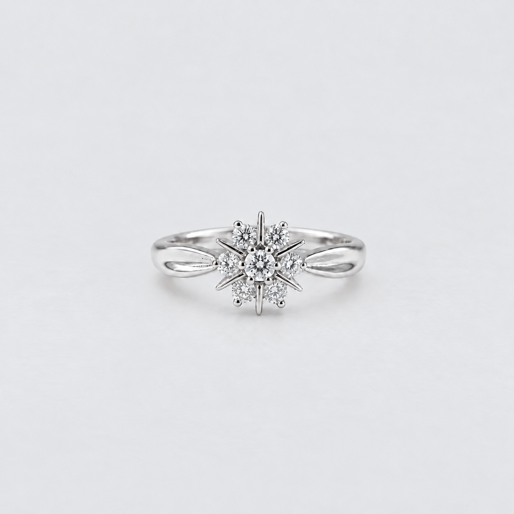 A silver snowflake ring with a central round diamond and smaller surrounding diamonds, set on a plain light gray background.