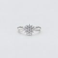A silver snowflake ring with a central round diamond and smaller surrounding diamonds, set on a plain light gray background.