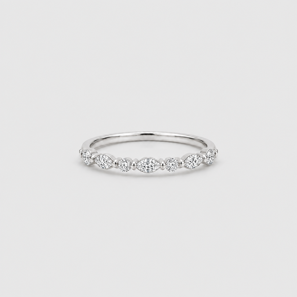 A delicate silver band ring featuring a row of small marquise-cut and round-cut clear stones across the top, photographed on a clean light gray background.