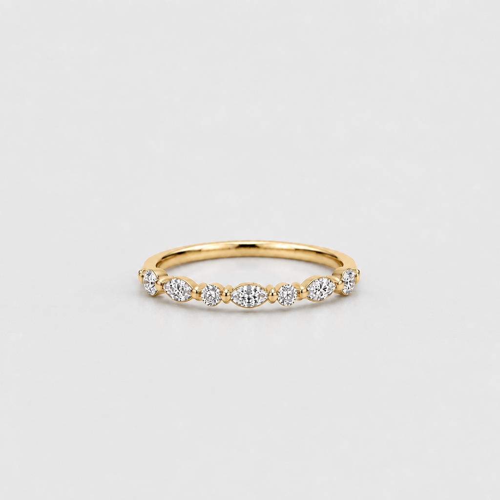 A yellow gold eternity ring featuring a row of round and marquise-cut clear gemstones, photographed on a clean, light gray background.
