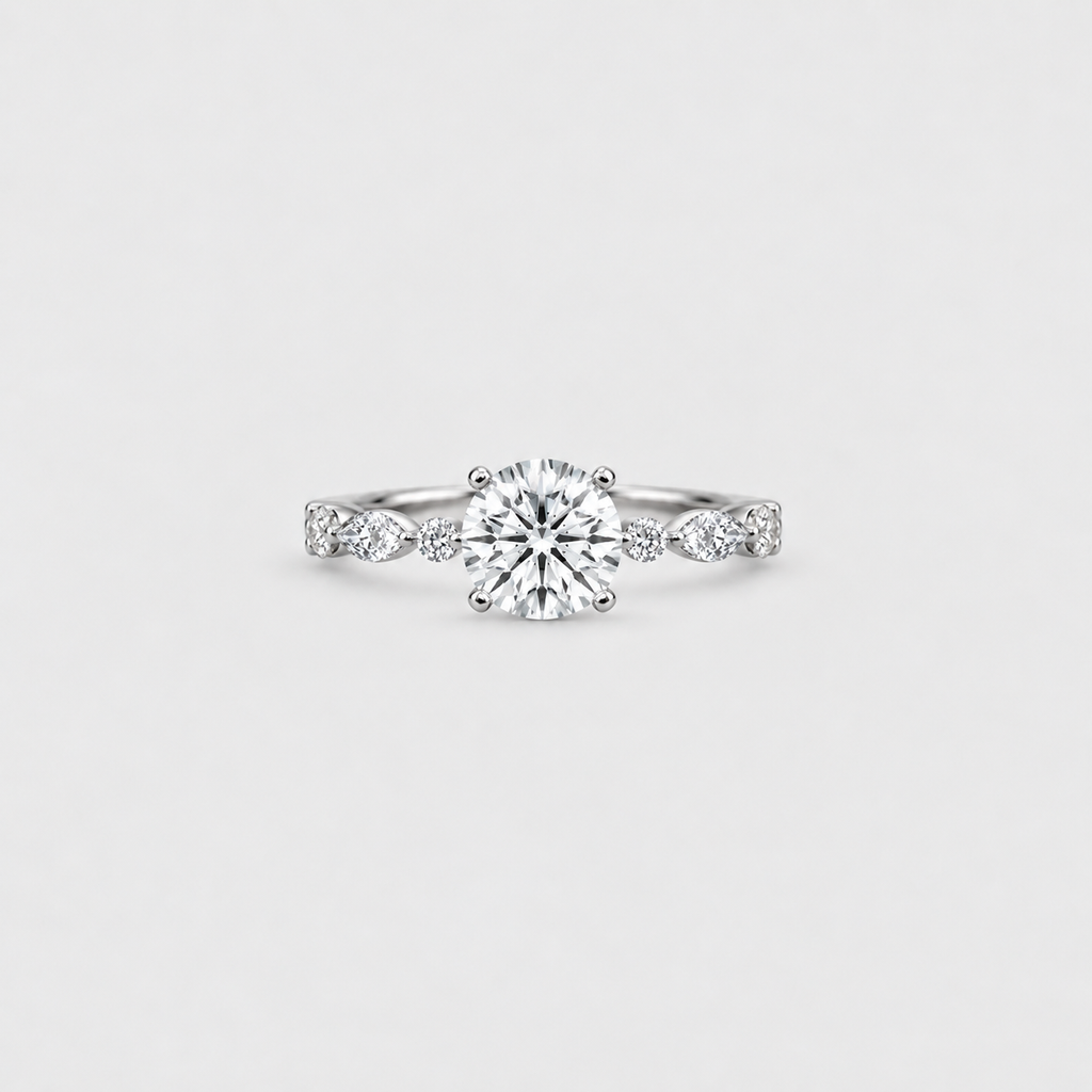 A silver engagement ring with a round-cut center diamond and small side diamonds on a plain light gray background.