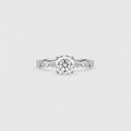 A silver engagement ring with a round-cut center diamond and small side diamonds on a plain light gray background.
