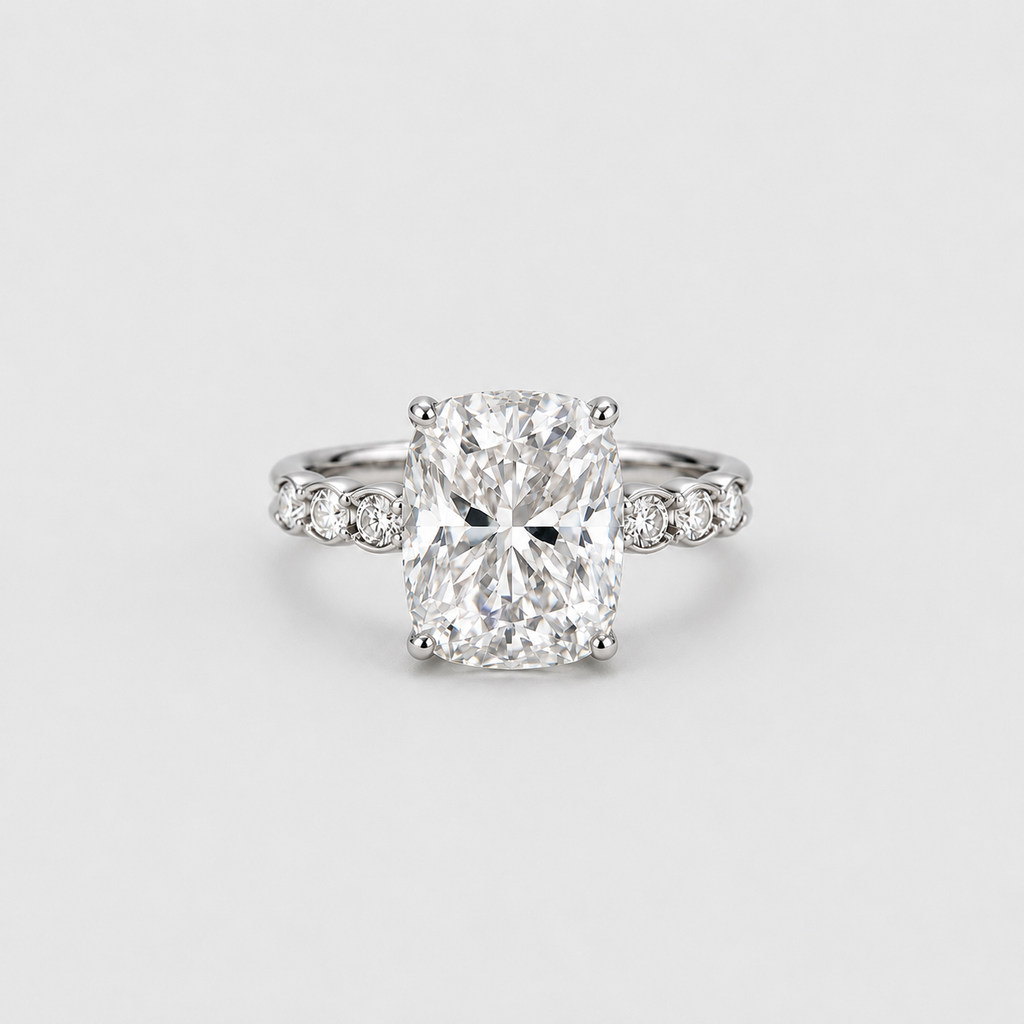 A radiant cut diamond engagement ring with a silver-colored band accented by small side diamonds, centered on a light gray background.