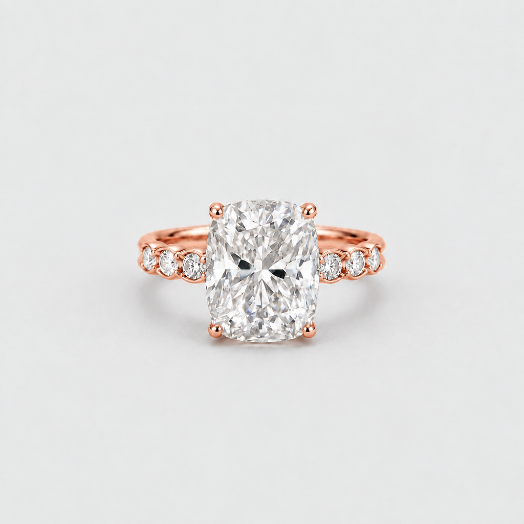 A rose gold engagement ring featuring a large cushion-cut diamond center stone and smaller diamonds set along the band, shown on a light gray background.