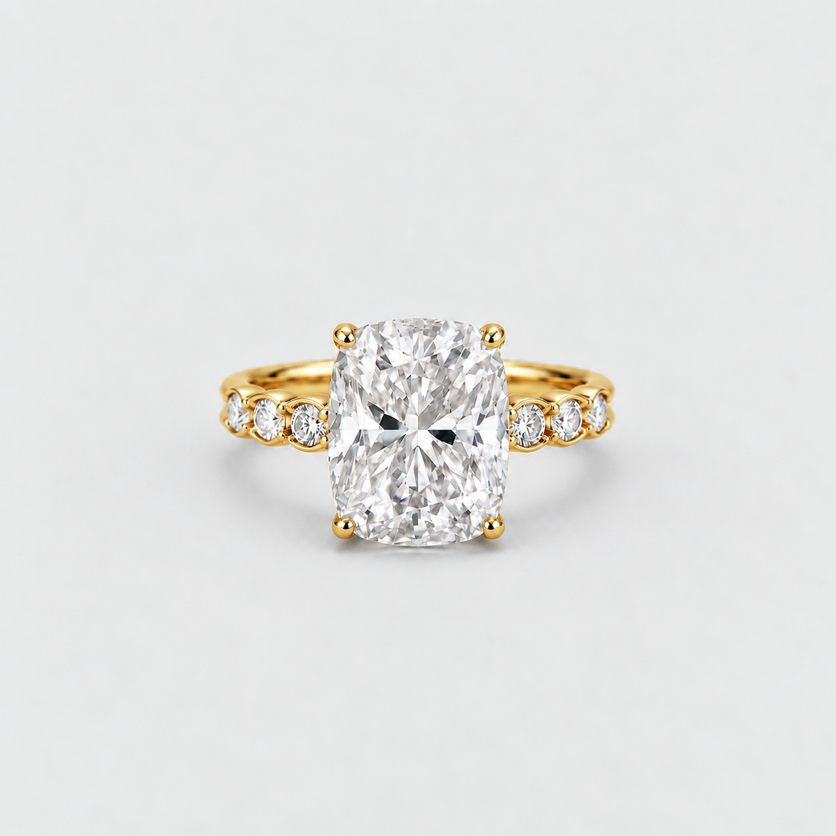 A yellow gold engagement ring featuring a large cushion-cut diamond center stone and smaller diamonds set along the shoulders, shown on a light gray background.