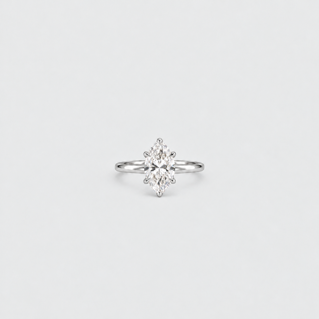 A silver engagement ring featuring a marquise-cut diamond center stone in a prong setting, shown against a clean, light gray background.