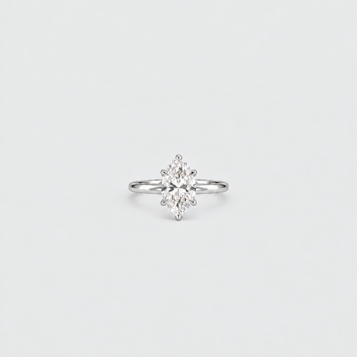 A silver engagement ring featuring a marquise-cut diamond center stone in a prong setting, shown against a clean, light gray background.