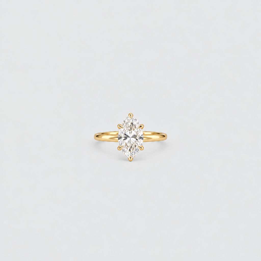 A yellow gold ring featuring a marquise-cut clear gemstone in a prong setting, centered on a light gray background.