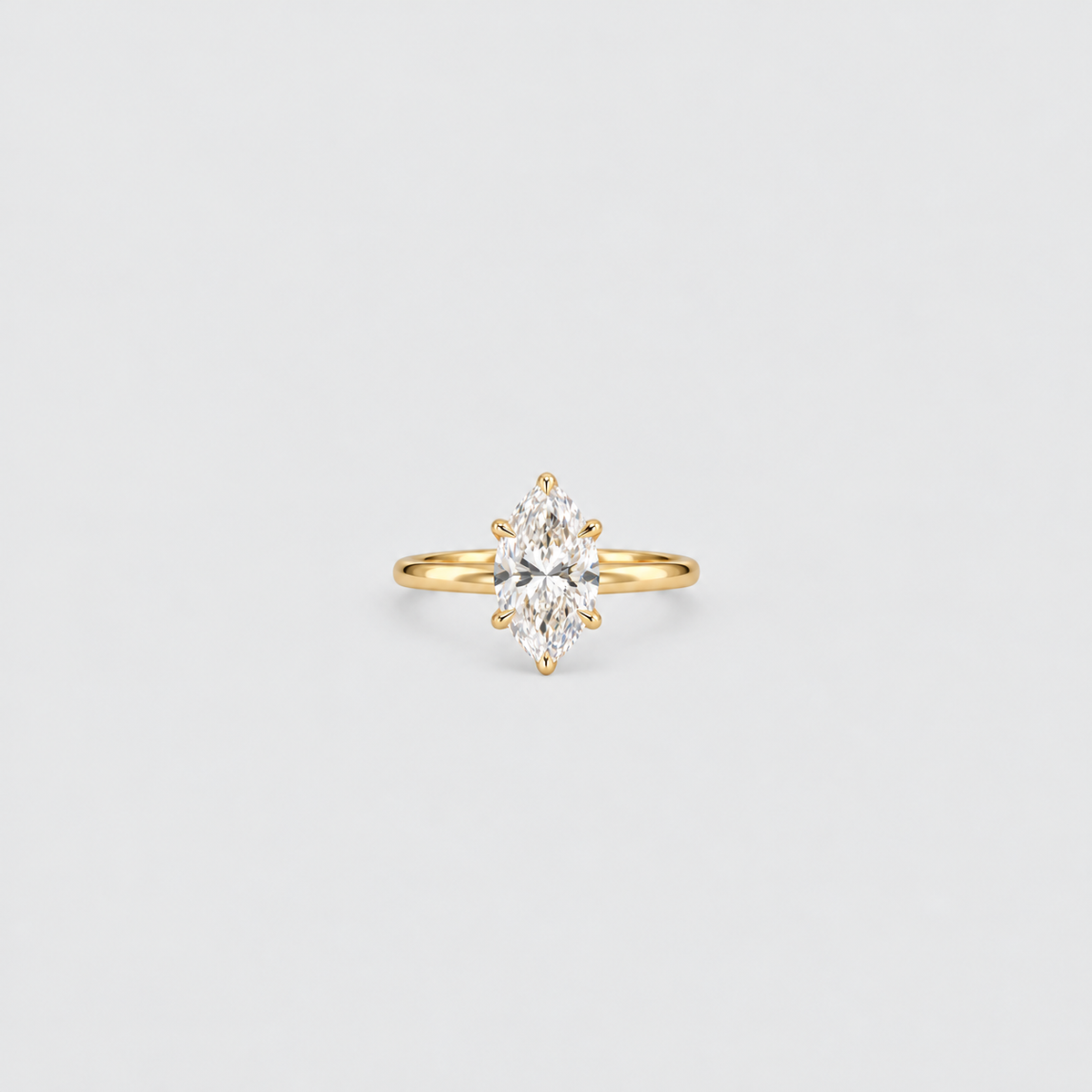 A yellow gold ring featuring a marquise-cut clear gemstone in a prong setting, centered on a light gray background.