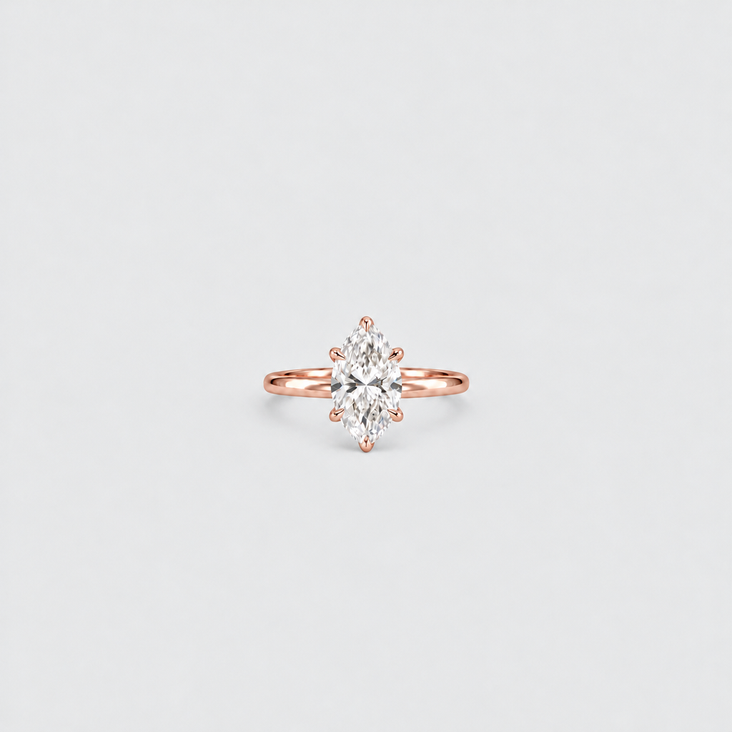A rose gold ring with a marquise-cut diamond center stone, set against a clean, light gray background.