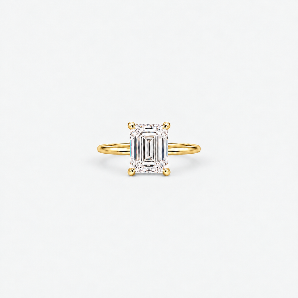 A yellow gold ring featuring an emerald-cut diamond center stone in a four-prong setting, shown against a clean white background.