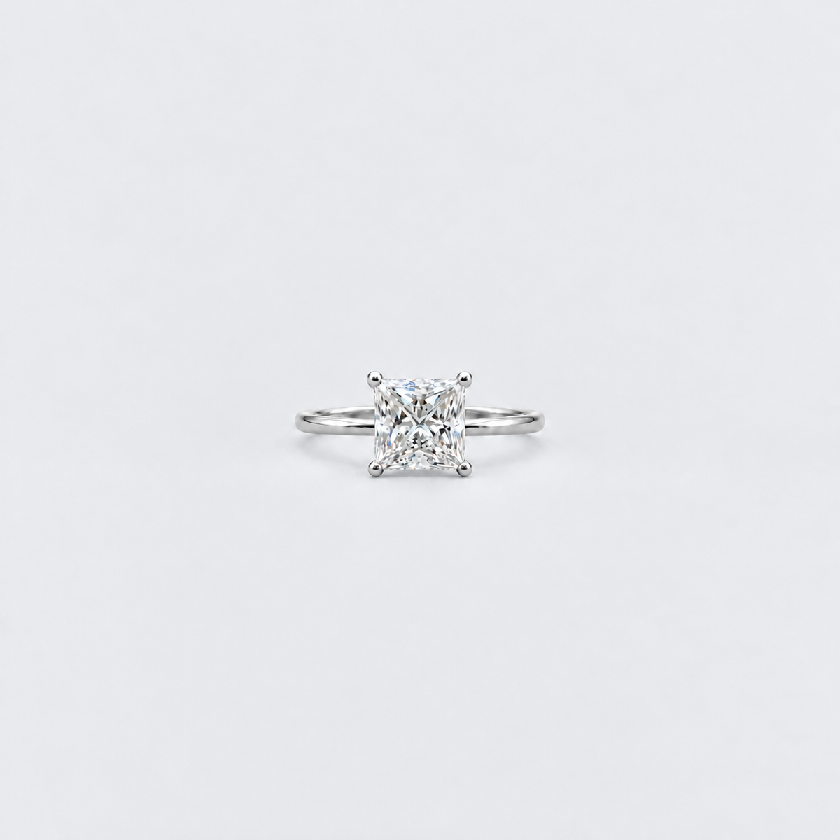 A classic solitaire engagement ring featuring a brilliant round-cut diamond set in a silver-colored metal band, centered on a clean white background.
