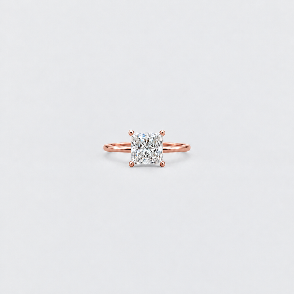 A single-prong rose gold ring with a square radiant-cut clear gemstone, centered on a light gray background.