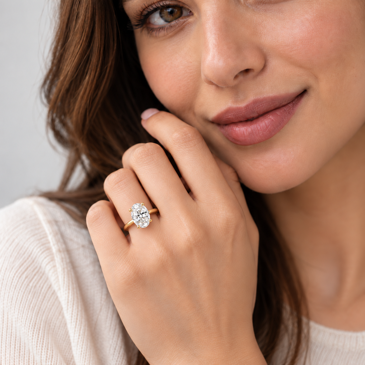 Oval cut solitaire diamond engagement ring on a yellow gold band worn by a woman