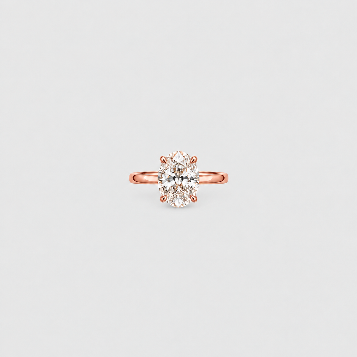 A rose gold solitaire engagement ring with a round brilliant-cut diamond center stone, set against a clean, light gray background.
