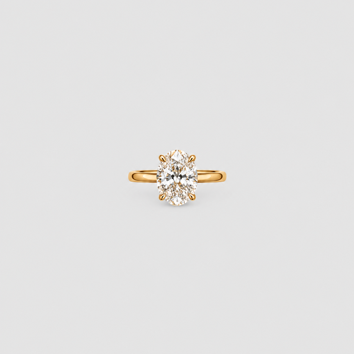 A yellow gold solitaire ring featuring an oval-cut clear gemstone in a four-prong setting, centered on a light gray background.
