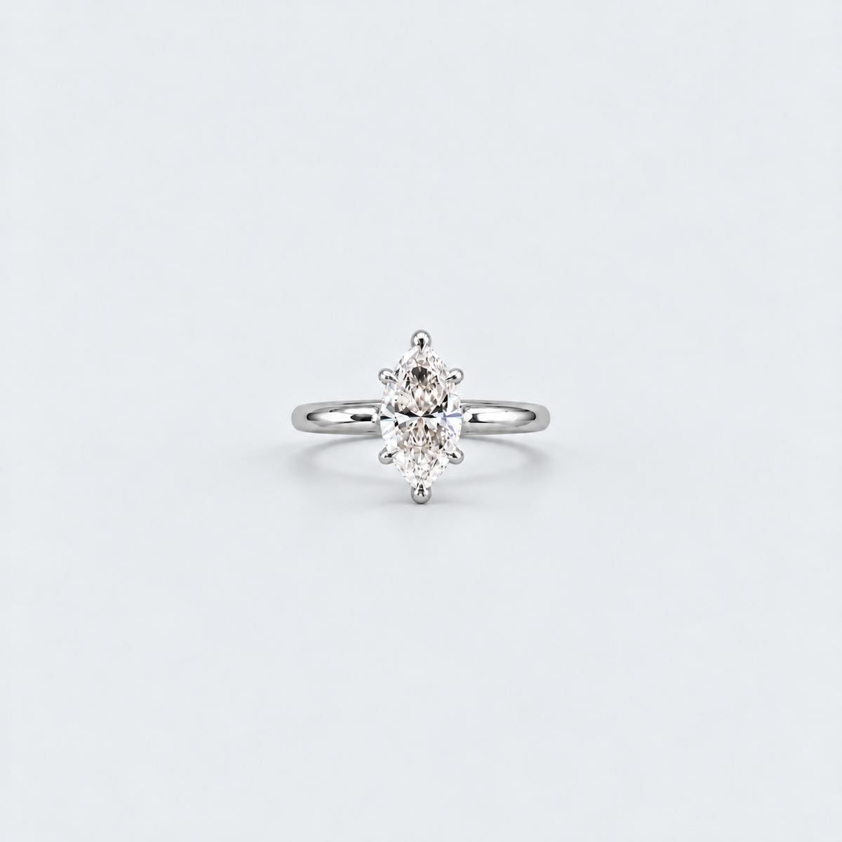 A silver solitaire ring featuring a marquise-cut diamond, set against a clean, light gray background.