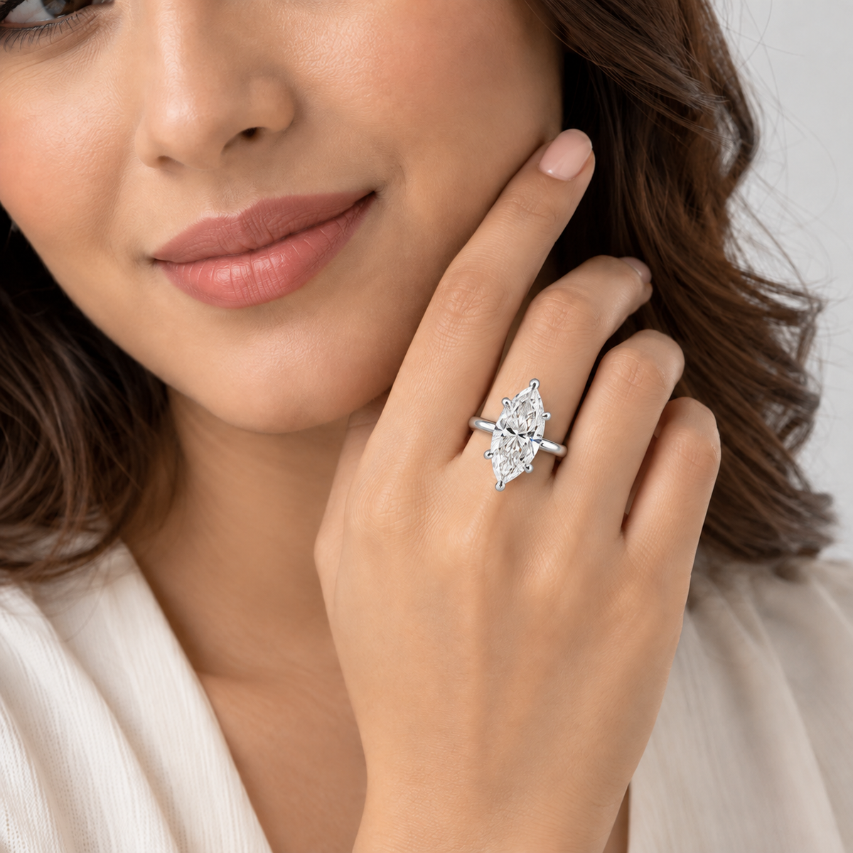 A close-up lifestyle shot of a woman wearing a silver ring with a marquise-cut clear gemstone on her finger.