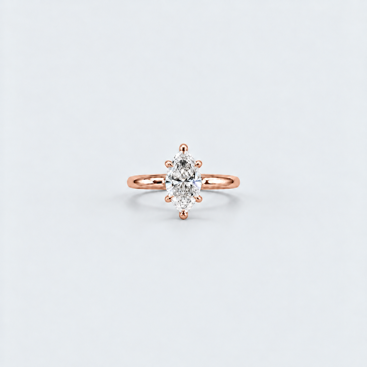 A rose gold ring with a marquise-cut diamond set in a six-prong setting, centered on a light gray background.