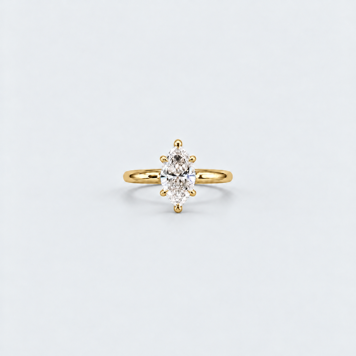 A yellow gold ring featuring an oval-cut clear gemstone in a prong setting, centered on a light gray background.