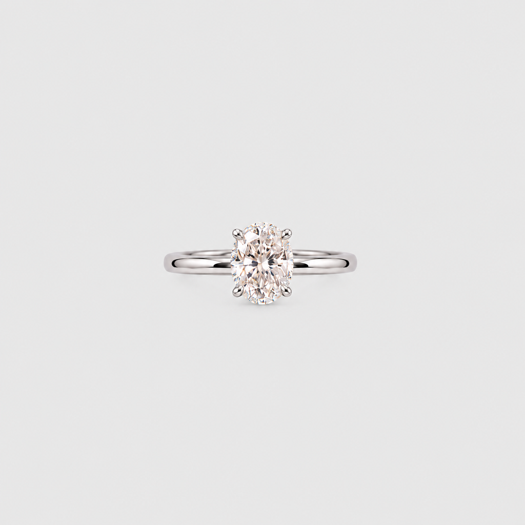 A classic solitaire engagement ring featuring an oval-cut diamond set in a polished white gold or platinum band, centered on a light gray background.