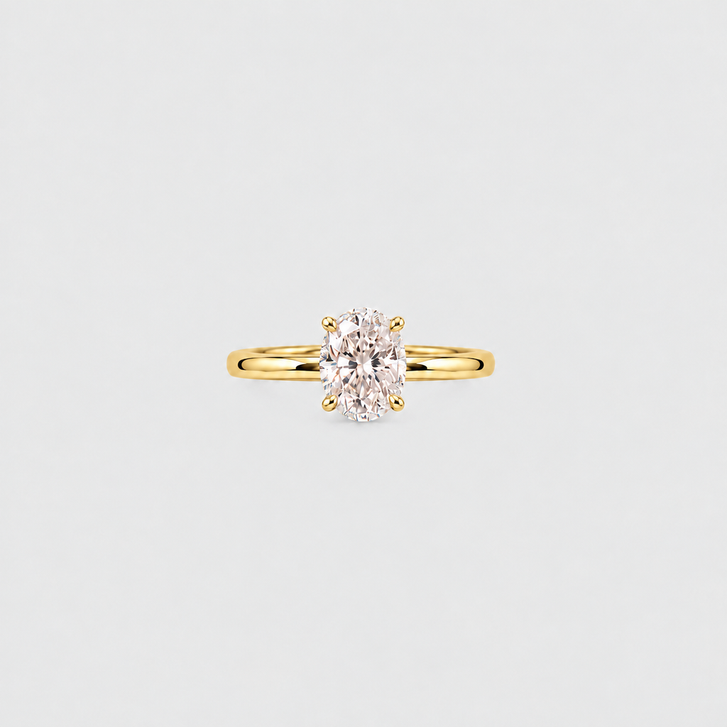 A yellow gold solitaire ring featuring an oval-cut clear gemstone in a four-prong setting, centered on a light gray background.