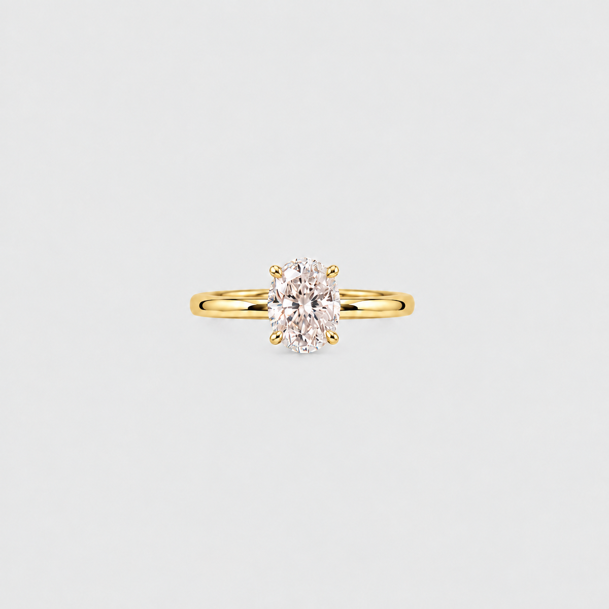 A yellow gold solitaire ring featuring an oval-cut clear gemstone in a four-prong setting, centered on a light gray background.