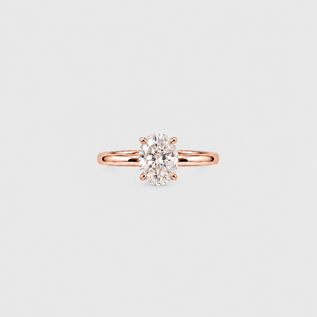 A rose gold solitaire ring with an oval-cut diamond set in a four-prong setting, centered on a light gray background.