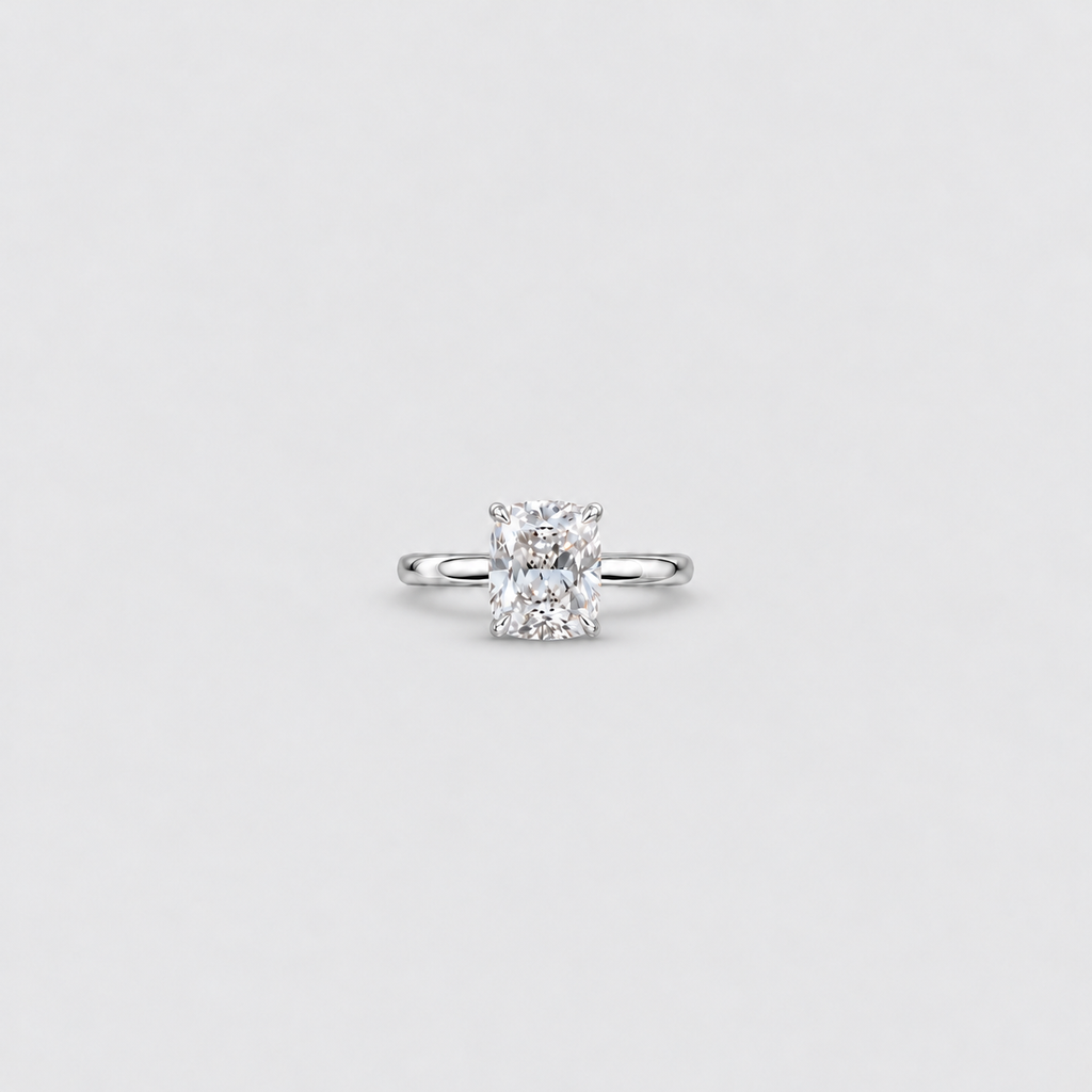An engagement ring featuring a radiant-cut diamond set in a polished white gold or platinum band, centered on a light gray background.