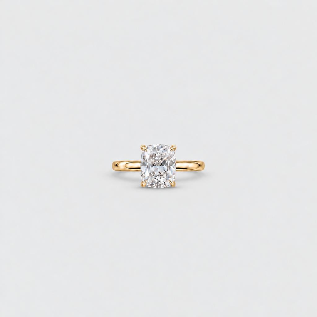 A yellow gold solitaire engagement ring featuring a large cushion-cut diamond, centered on a light gray background.